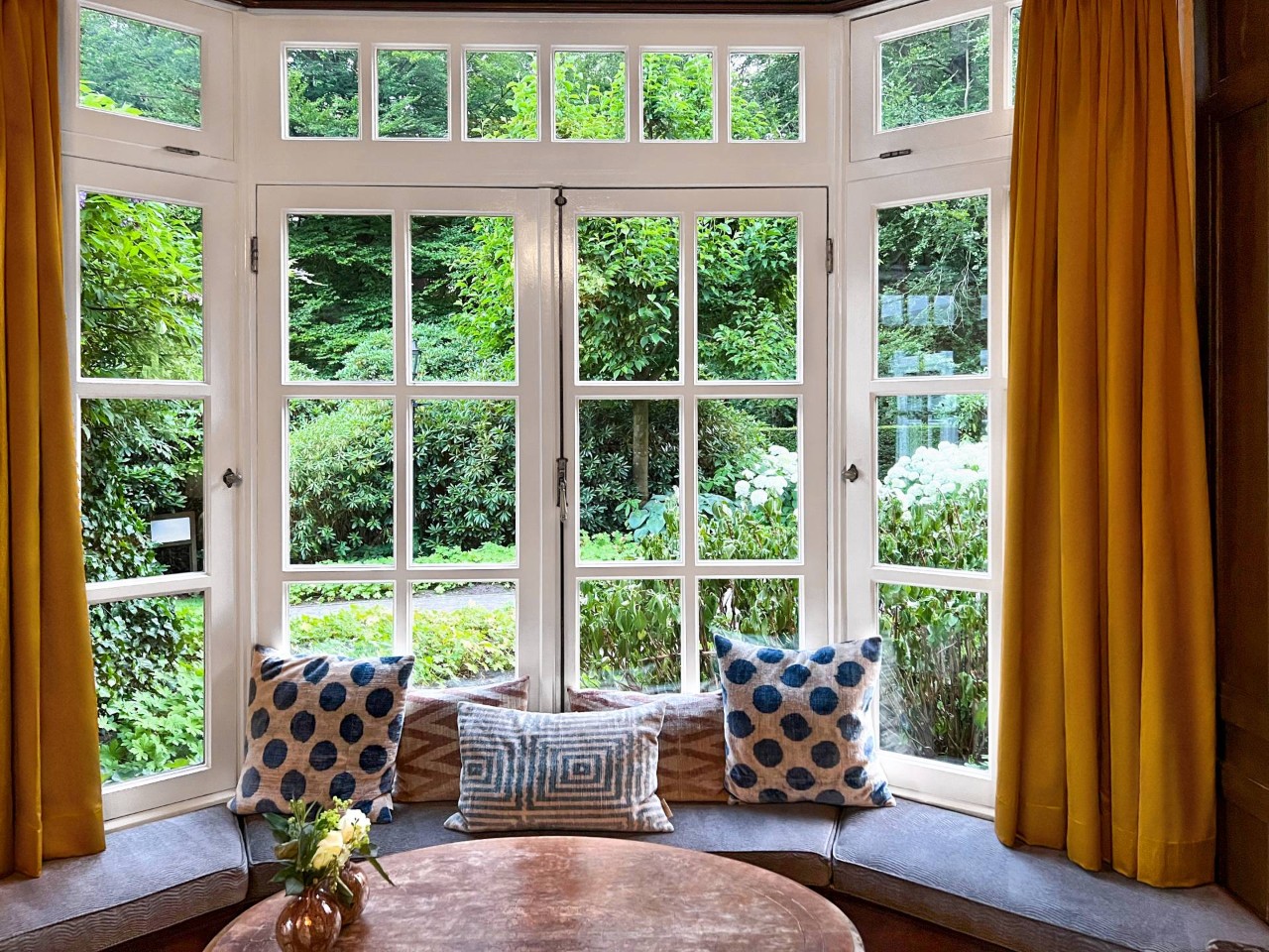 Small wooden table set near a bay window dressed with yellow curtains near Jupiter, FL