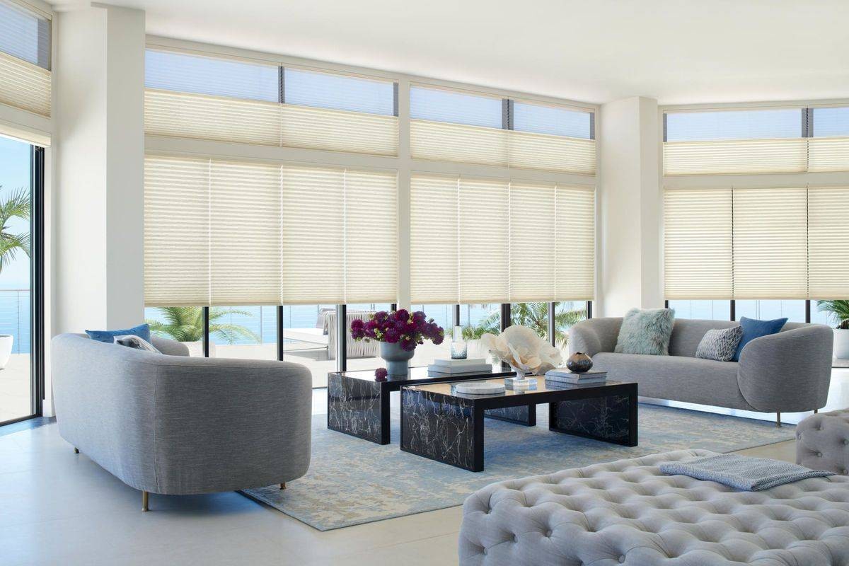 A living room equipped with white Hunter Douglas Duette® Cellular Shades and gray furniture near Jupiter, FL 