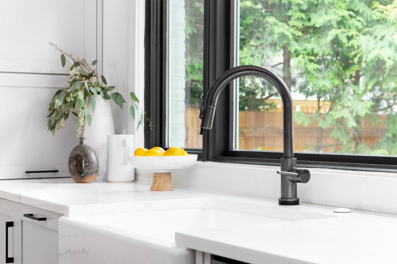 A sleek black and white kitchen with a sink below a window without durable window treatments at Custom Window Decor of Jupiter near Jupiter, FL