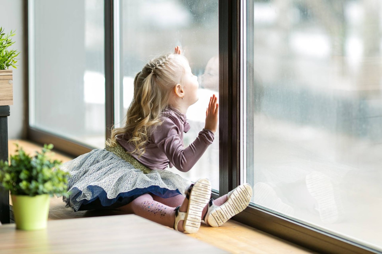A child sitting at a window with nearby plants at Custom Window Decor of Jupiter near Jupiter, FL